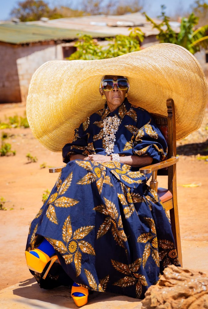 Margret Chola in a big hat and dress